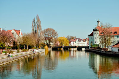 Buildings by river against clear sky