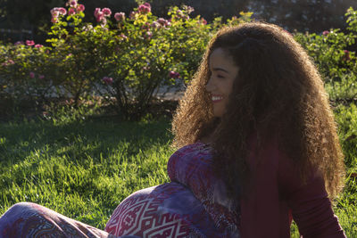 Smiling pregnant woman sitting on field