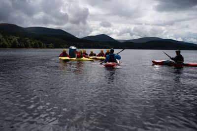 People on boat in river against sky