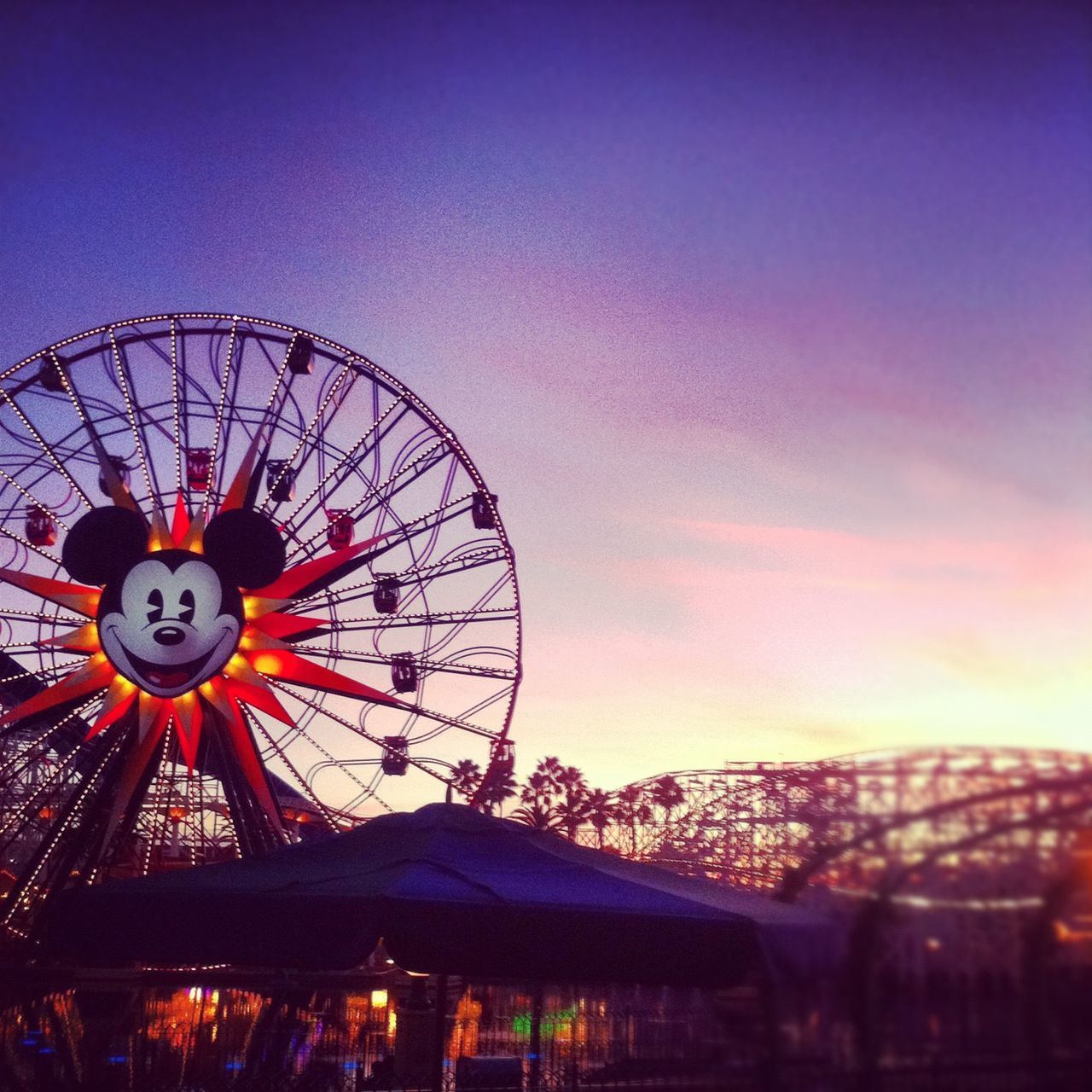 FERRIS WHEEL AGAINST ILLUMINATED SKY AT SUNSET