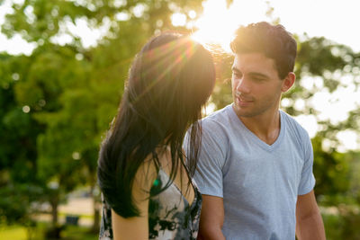 Young couple kissing against trees