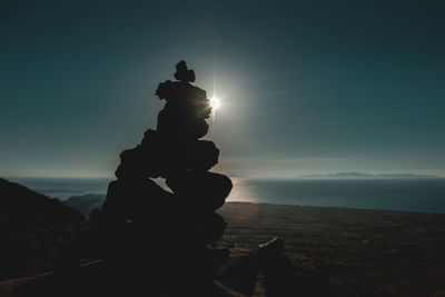 Stack of rocks on mountain against sky during sunset