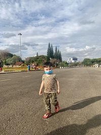 Boy playing with umbrella against sky