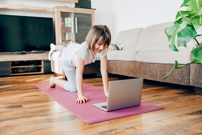 The girl performs sports exercises at home. online workouts. mobility of children 