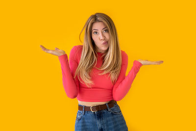 Portrait of young woman standing against yellow background