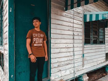 Boy standing against closed door of house