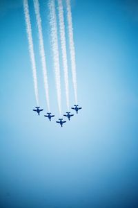 Low angle view of airplane flying against clear blue sky