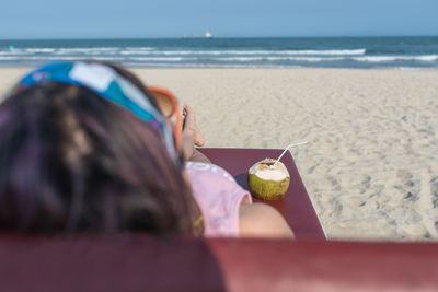 Rear view of woman sitting at beach