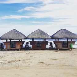 Stilt houses on beach against sky