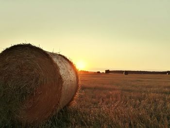 Hay bales on field against sky during sunset