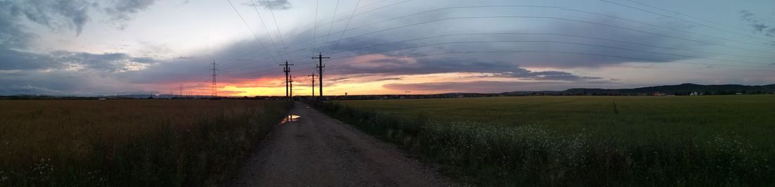 Road amidst field against sky during sunset