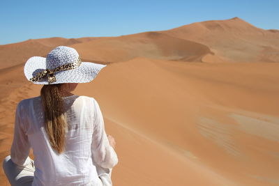 Rear view of woman in desert against clear sky