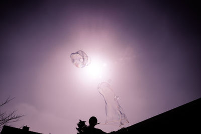 Low angle view of silhouette man against illuminated sky at night