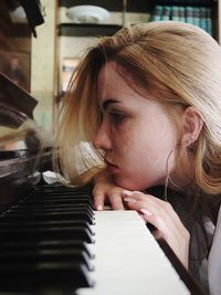 Close-up of teenage girl leaning on piano keys