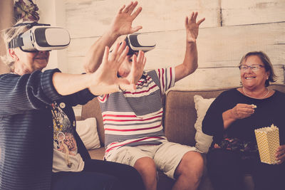 Senior couple wearing virtual reality simulator with woman at home