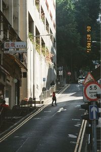 Rear view of man walking on road against buildings