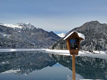 Religious structure against snowcapped mountains reflecting on lake