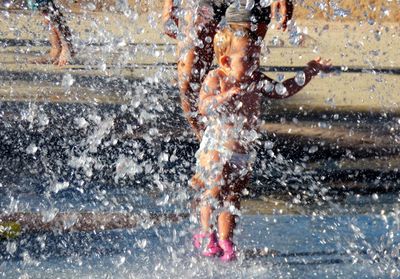 Baby girl enjoying splashing water in fountain during summer