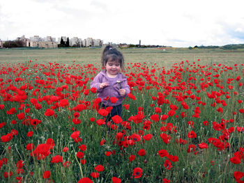 Cute girl standing amidst red flowering field