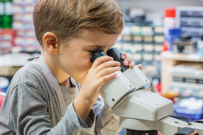 Side view of boy looking through microscope in laboratory