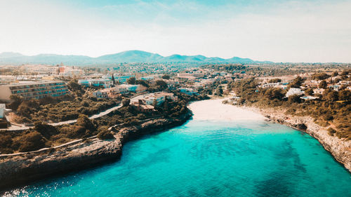 Aerial view of city by sea against sky