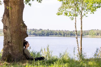 Side view of woman sitting on tree
