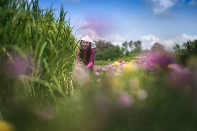 Woman standing on purple flowering plants on field