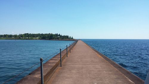 Pier over sea against clear blue sky