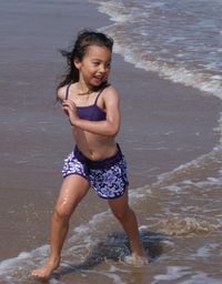 Full length of happy girl running on shore at beach