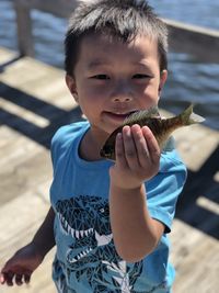 Portrait of cute boy holding fish while standing on land