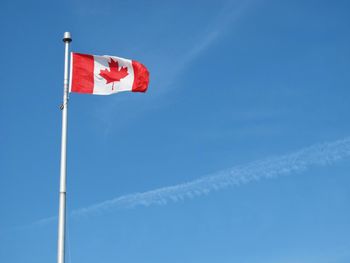 Low angle view of flag against blue sky