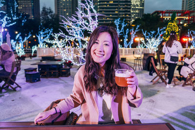 Portrait of smiling young woman drinking glass