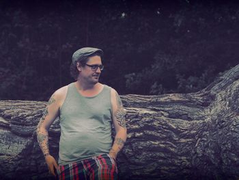 Hipster standing against log in forest