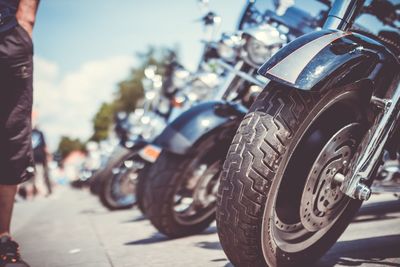 Cropped image of man standing by motorcycles parked on street