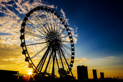 Low angle view of ferris wheel against sky during sunset