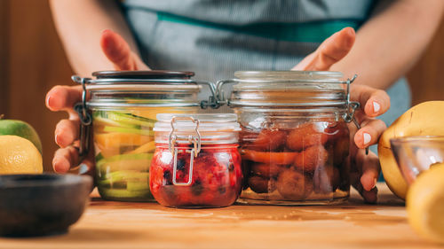 Woman holding jars with fermented fruits.