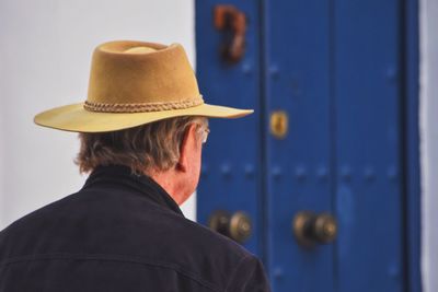 Close-up of man wearing hat against door
