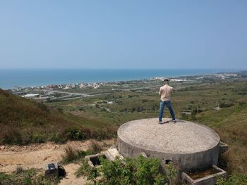 Rear view of man looking at sea against clear sky