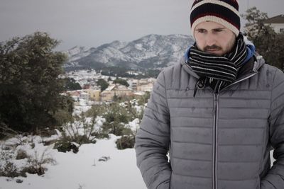 Portrait of young man standing on snow covered field