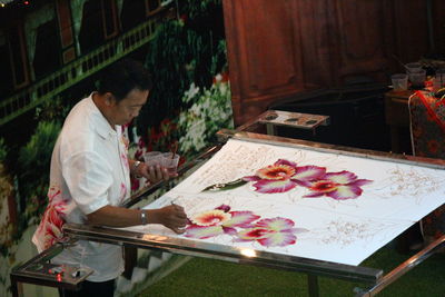 Side view of man holding flower bouquet on table