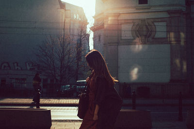 Side view of woman walking on street in city