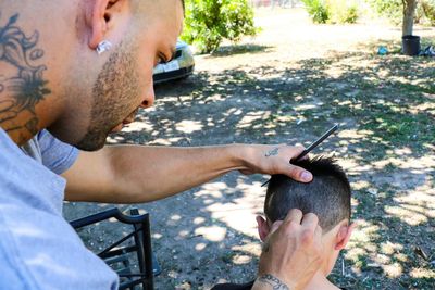 Barber cutting hair of customer outdoors