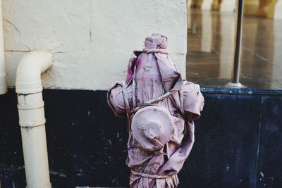 Close-up of abandoned statue by wall against building