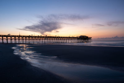 Pier over sea against sky during sunset