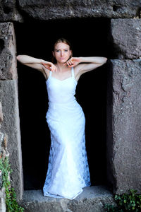 Sad young woman wearing white dress standing on doorway