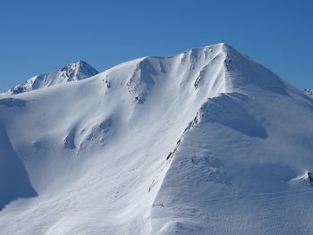 Scenic view of snowcapped mountains against clear blue sky