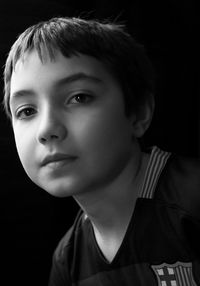 Close-up portrait of boy against black background