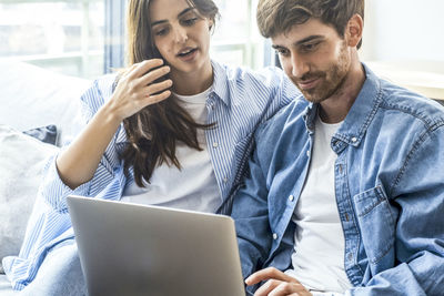 Portrait of smiling friends using laptop at home