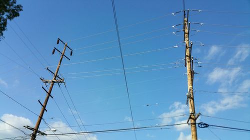 Low angle view of electricity pylon against blue sky