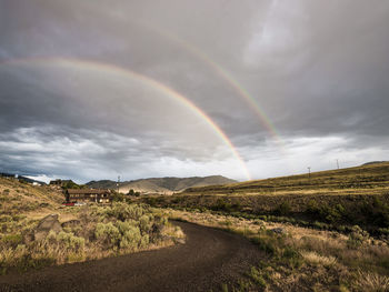 Scenic view of rainbow over landscape against sky